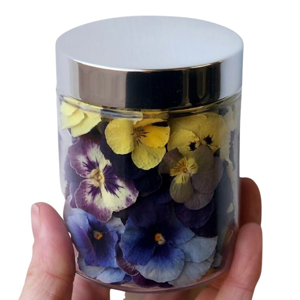 Jar of freeze dried edible violas held in hand.